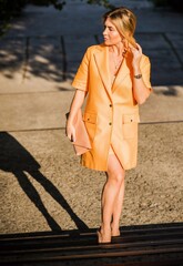 Fashionable woman in orange trench. Woman in coat at street, woman outfit. Fancy style for ladies, autumn colors and fashion details 