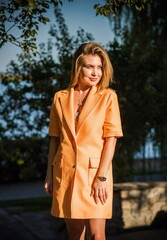 Fashionable woman in orange trench. Woman in coat at street, woman outfit. Fancy style for ladies, autumn colors and fashion details 