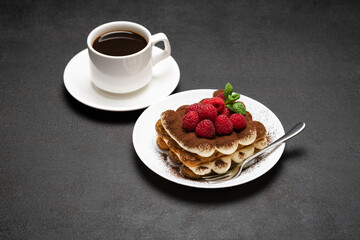 portion of Classic tiramisu dessert with raspberries and cup of coffee dark concrete background