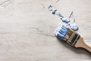 A blue paint brush lies on a gray wooden background old and splashes of paint spilled