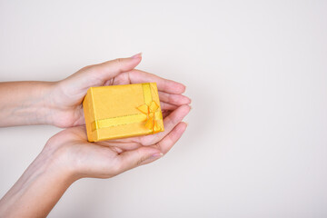 Yellow gift box with bow ribbon in woman hands on the white background, birthday, Christmas, Valentine day concept. accept gifts concept