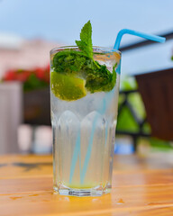 Cold summer fruit and berries lemonade. Mojito lemonade in a glass with a plastic straw outside.