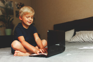child does homework , lying in bed using his laptop or skyping.