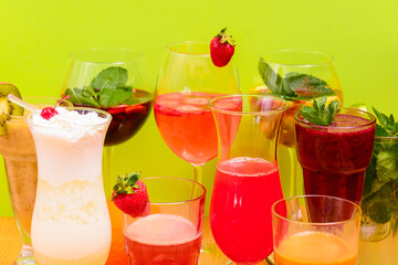 Summer drinks with fruit juice and ice. Refreshing summer beverages in different glasses over green background.