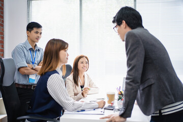 Young Asian people are joining a team for a business meeting in the office.