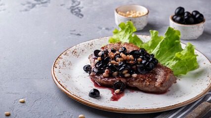 Roasted beef with black olives, nuts and red sauce on a plate. Copy space