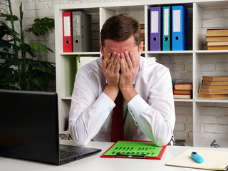 Tired and pensive businessman covered his face with his hands while reading the audit results.