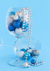 Christmas baubles in a wine glass on a light blue background