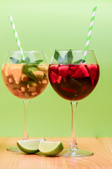 Summer drinks with fruit juice and ice. Refreshing summer beverages in different glasses over green background.