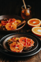 Orange dessert with wine honey or maple syrup and ginger spice, decorated pomegranate berries. Wonderfully sweet, rich and fresh food. Dark rustic background, copy space for you text