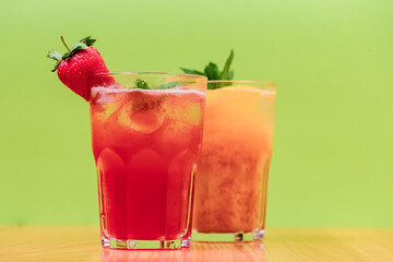 Summer drinks with fruit juice and ice. Refreshing summer beverages in different glasses over green background.