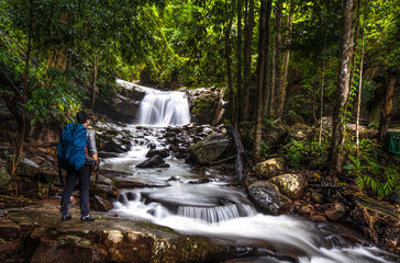 Hikers young men backpacker looking at the waterfall in the forest at  Phu Soi Dao National Park, Thailand.