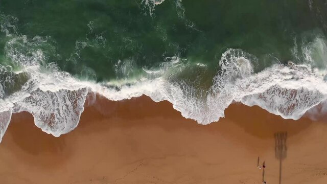 Aerial drone footage of beach waves, brown sand and emerald water color are contrasted. Beautiful nature footage is 4K 30fps.