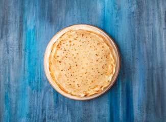 Thin pancakes on blue background . Top view. Copy space