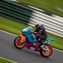 A panning shot of a racing bike cornering as it circuits a track.