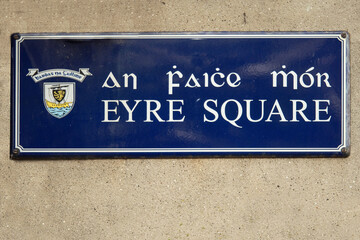 Naklejka premium Sing Eyre Square in Irish and English language with town emblem on a light color wall. Galway city, Ireland