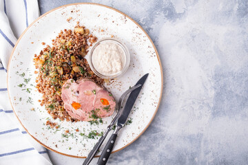Boiled pork with buckwheat cereal served with fork and knife. Top view, text space