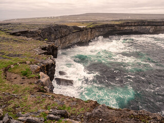 Atlantic ocean crushes powerful waves on cliff rocks. Landscape in Inis mor Aran Islands, county Galway, Ireland.