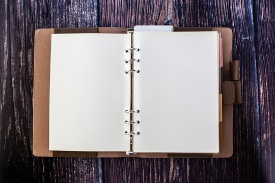 An Open Blank Planner, Spiral Binders With Leather Cover And Colorful Tabs Index, Isolated On Wood Table.