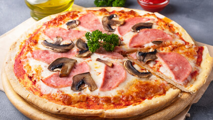 Homemade pizza with mushrooms and ham on a wooden board. Closeup