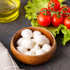 Delicious mozzarella cheese in a wooden bowl with tomatoes and olive oil.