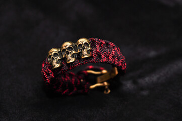 Braided paracord bracelet red and black camouflage with a clasp and insert made of bronze three skulls three dead kings - Powered by Adobe