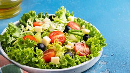 Dieting healthy salad with greens, cherry tomatoes. onion, cheese and black olives. Concept of  healthy vegetarian meal. Copy space