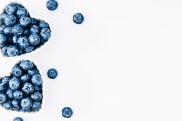 Plate in shape of heart with blueberries on white background. Blueberry berries background. Valentines Day concept. Flat lay, top view, copy space