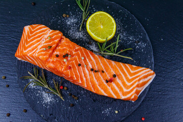 Raw salmon fillet with spices on black slate. Top view