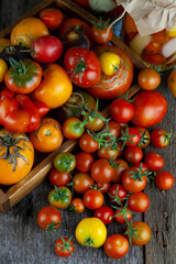Tomatoes, peppers, onions on the table.Autumn harvest of vegetables. Glass jar with pickled tomatoes. Wooden background. Vegetable food. Still life. Tomato of different varieties. Top view.