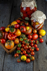 Tomatoes, peppers, onions on the table.Autumn harvest of vegetables. Glass jar with pickled tomatoes. Wooden background. Vegetable food. Still life. Tomato of different varieties. Top view.