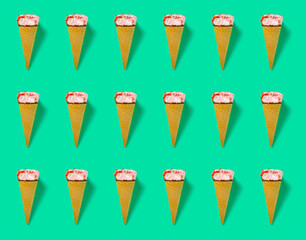 seamless pattern of strawberry flavor ice cream cone with a bite on green as background