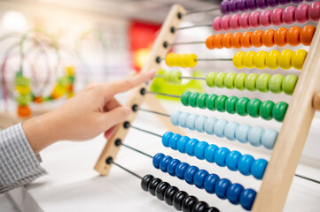 Male hand calculating with beads on wooden rainbow abacus for number calculation. Mathematics learning concept - obrazy, fototapety, plakaty