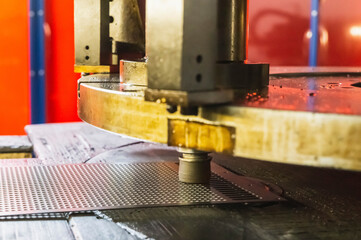 stamp machine that makes many holes in a metal sheet in a factory