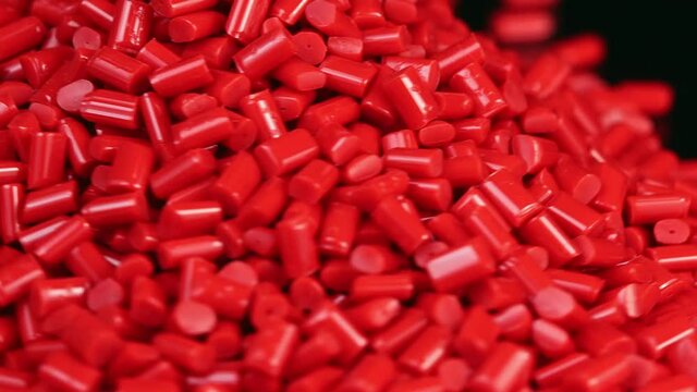 Close-up rotation of Red plastic polymer granules on black background
