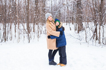 Fototapeta na wymiar Portrait of happy mother with child son in winter outdoors. Snowy park. Single parent.
