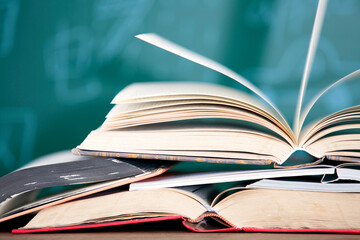 A stack of books opened in front of the blackboard