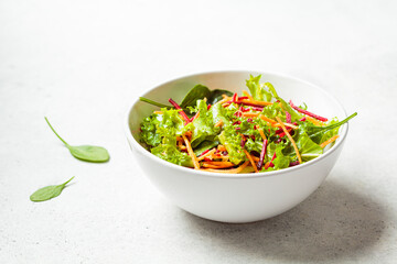 Healthy green salad with beet and carrot in white bowl. Diet food concept.