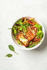 Green salad with grilled halloumi cheese, beet and carrot in a white bowl, top view. Cypriot or Greek food concept.