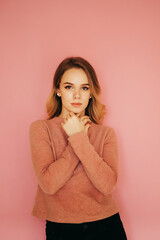 Beautiful young woman standing on a pink background and posing for the camera. Vertical photo.