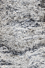 Scratched foil background. Metallic crushed texture. Shiny silver wrinkled surface.