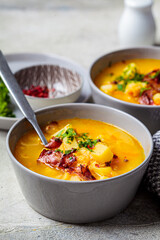 Pea soup with bacon and parsley in gray bowls, gray background.