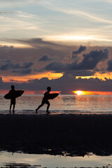 Niños haciendo surf en la playa con atardecer de fondo