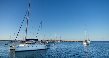 Fototapeta premium Panoramic of a catamaran anchored on a beach in the Formentera island during sunset. Calm ocean water in the coast in the mediterranean sea.