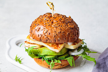 Grilled halloumi burger with slices of avocado and arugula. Vegetarian food concept.
