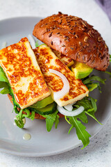 Grilled halloumi burger with slices of avocado and arugula. Vegetarian food concept.