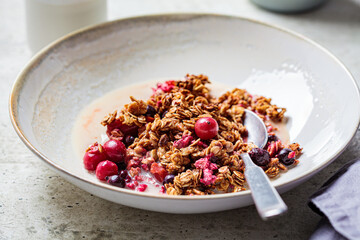 Vegan breakfast - baked oatmeal with berries and oat milk in white bowl.