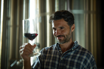 Authentic shot of happy successful male winemaker is tasting a flavor and checking red wine quality...