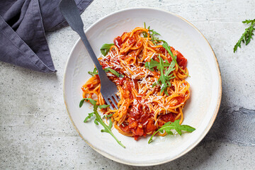 Pasta with tomato sauce, cheese and arugula in white bowl, top view. Traditional Italian cuisine concept.