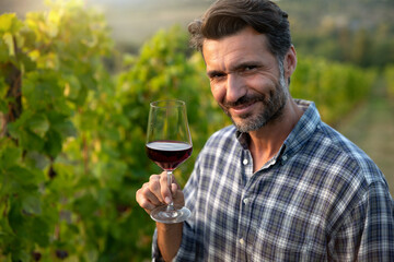 Authentic shot of happy successful male winemaker is tasting a flavor and checking red wine quality...